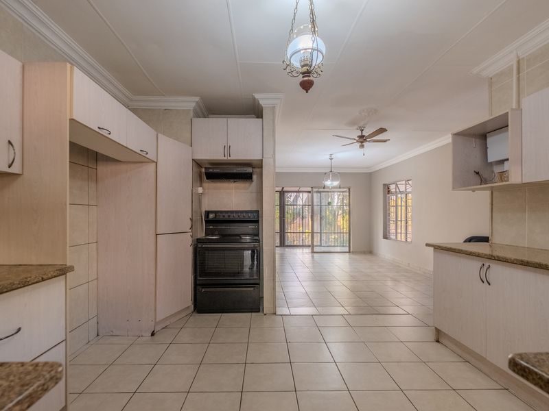 Spacious open-plan kitchen and living area featuring tiled flooring, built-in cabinetry with granite countertops, and direct access to the rear patio through sliding doors.