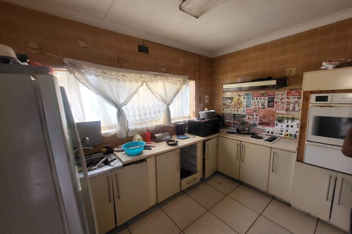 A dated kitchen featuring built-in cabinetry, an integrated oven, and hob. The space requires modernization of finishes and fixtures to improve functionality and aesthetic appeal.