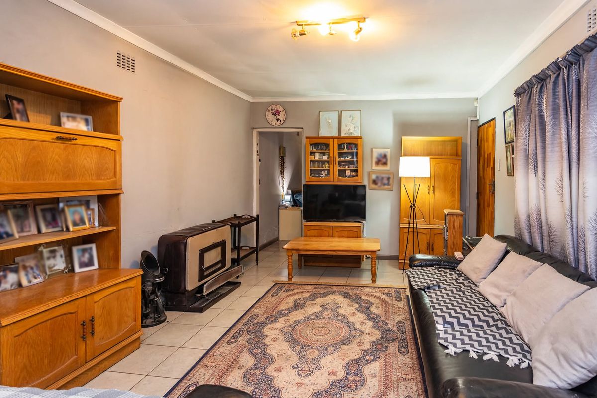 A living room featuring tiled flooring, a freestanding fireplace, and a ceiling-mounted light fixture, offering a functional and comfortable living space.