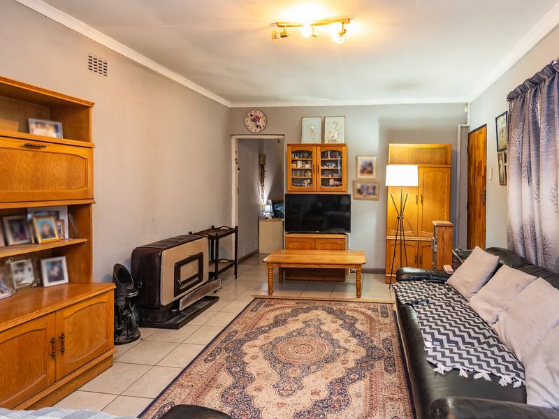 A living room featuring tiled flooring, a freestanding fireplace, and a ceiling-mounted light fixture, offering a functional and comfortable living space.