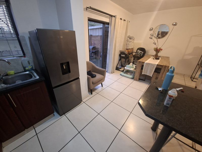 Open plan kitchen and dining area featuring tiled flooring, granite countertops, and direct access to the outdoor patio through a sliding glass door.