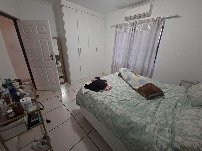 A bedroom featuring tiled flooring, a built-in wardrobe, and a wall-mounted split-system air conditioning unit.