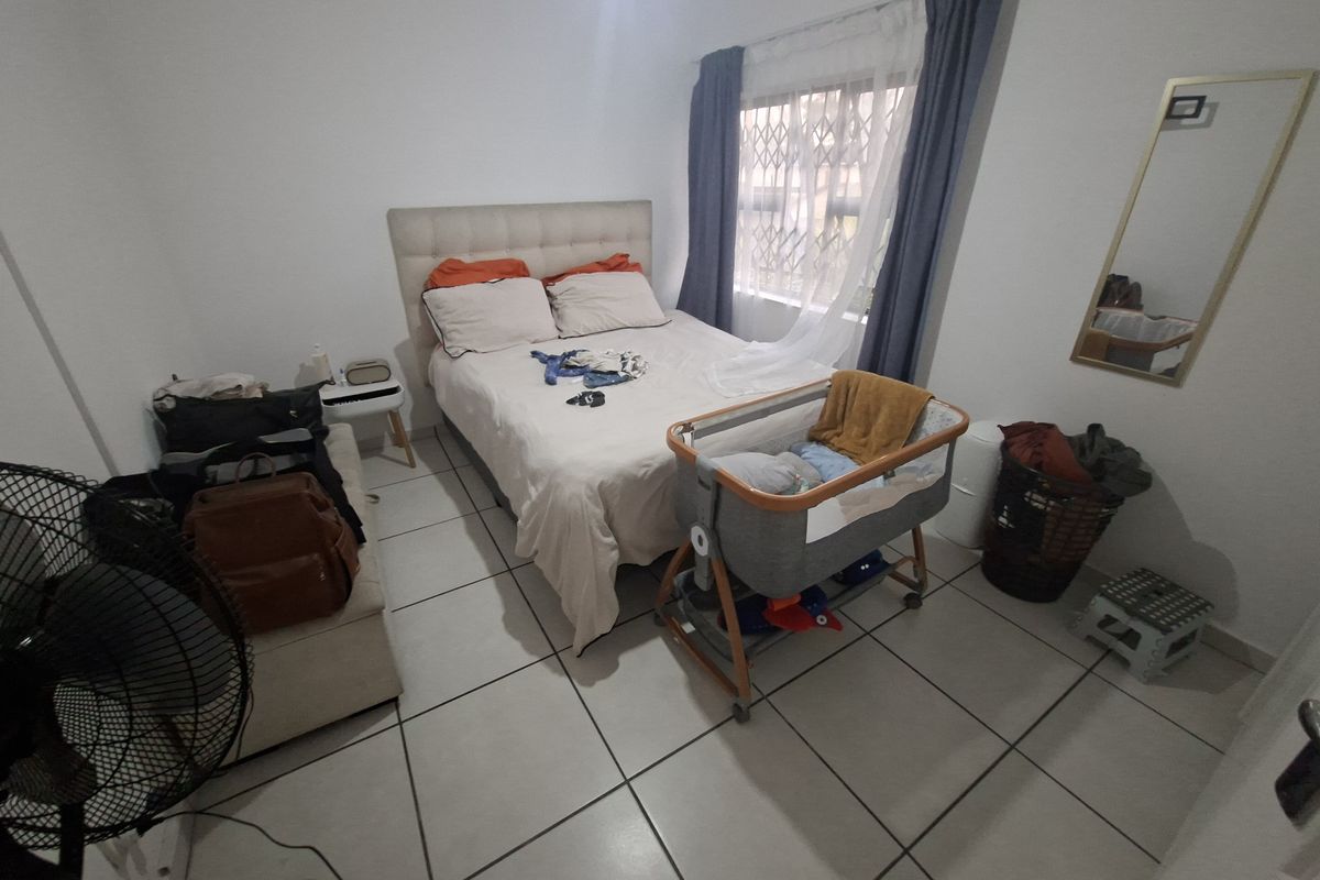 A functional bedroom featuring tiled flooring and a window fitted with a security gate, providing a practical space for rest.