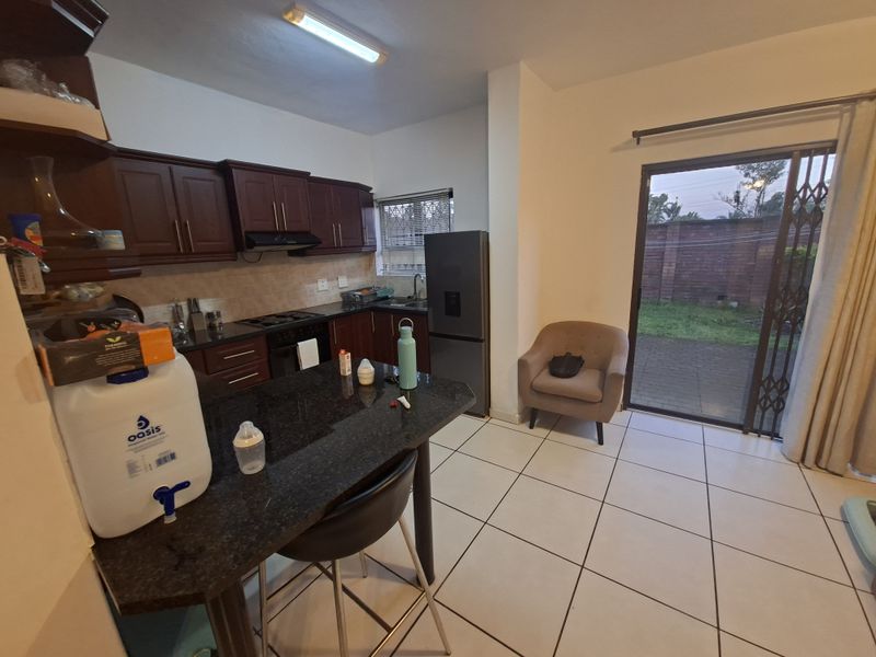 Open-plan kitchen featuring dark wood cabinetry, granite countertops, and tiled flooring, with direct access to the rear patio through a sliding glass door.