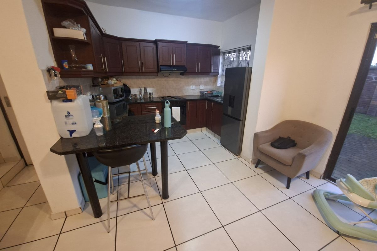 A functional kitchen featuring dark wood cabinetry, granite countertops, built-in cooking appliances, and tiled flooring with direct access to the outdoor area.