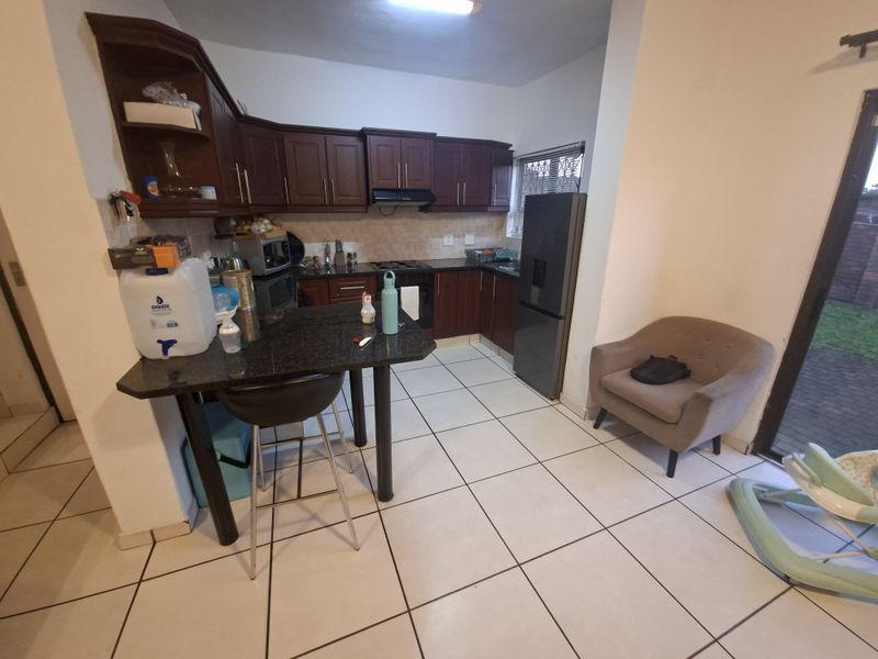 A functional kitchen featuring dark wood cabinetry, granite countertops, built-in cooking appliances, and tiled flooring with direct access to the outdoor area.
