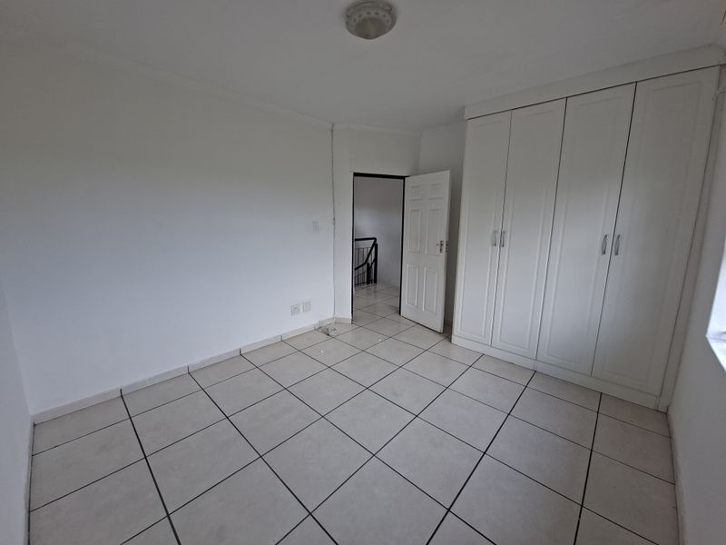 An empty bedroom featuring tiled flooring and built-in white cupboards, offering a blank canvas for personalization.