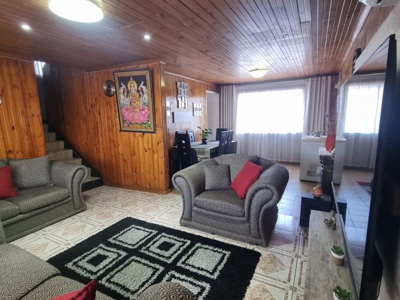 Open-plan living and dining area featuring extensive timber wall and ceiling paneling, ceramic tiled flooring, and integrated air conditioning.