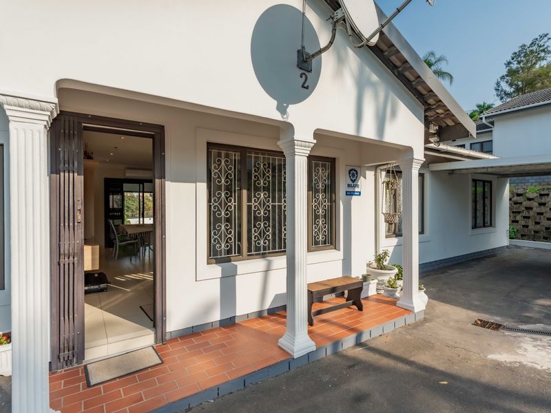 Front entrance of the townhouse featuring a covered porch with decorative columns, security gates, and tiled flooring.