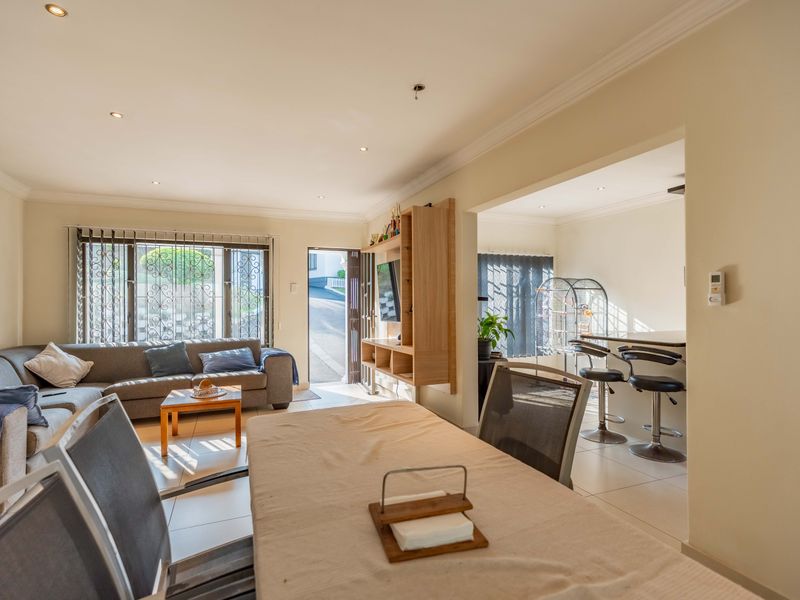 Spacious open-plan living and dining area featuring tiled floors, recessed lighting, and a breakfast bar, offering a functional layout for modern living.