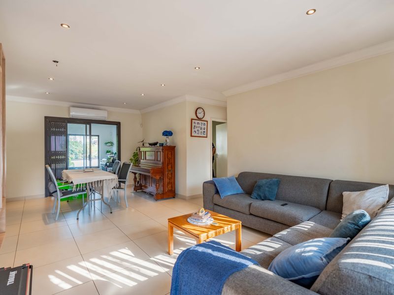 Spacious open-plan living and dining area featuring tiled floors, recessed lighting, and direct access to the patio through sliding glass doors.