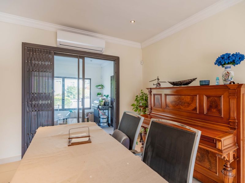 A well-maintained dining area featuring tiled flooring, crown molding, recessed lighting, and a split-system air conditioner, with direct access to an outdoor patio.