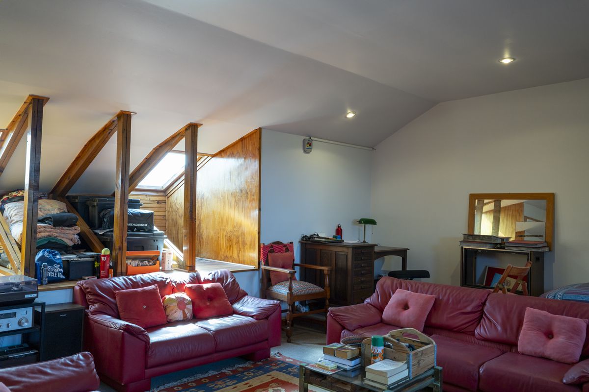 Spacious attic-style living room featuring exposed timber rafters, a skylight, and recessed downlighting, offering a unique architectural character.