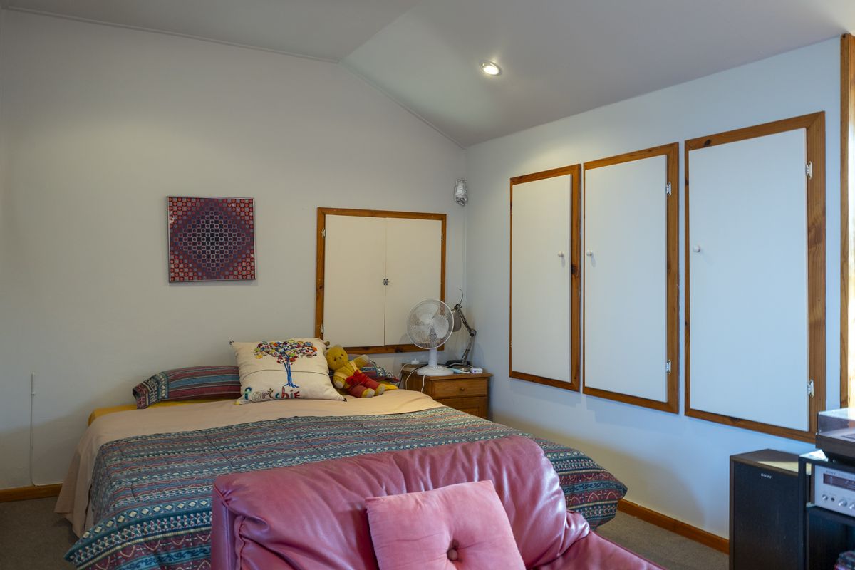 A bedroom featuring a vaulted ceiling, recessed lighting, and multiple built-in storage cupboards with wooden frames.