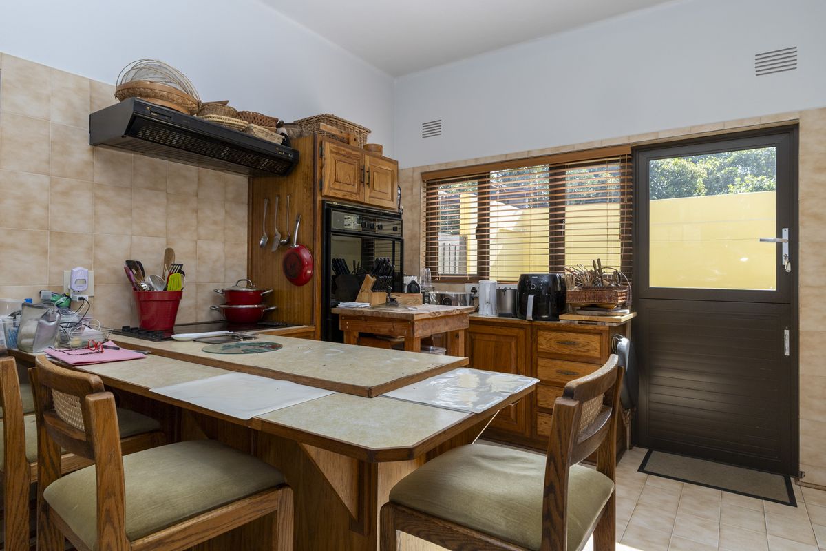 A functional kitchen featuring built-in wooden cabinetry, a tiled backsplash, integrated oven, and direct access to the exterior via a side door.