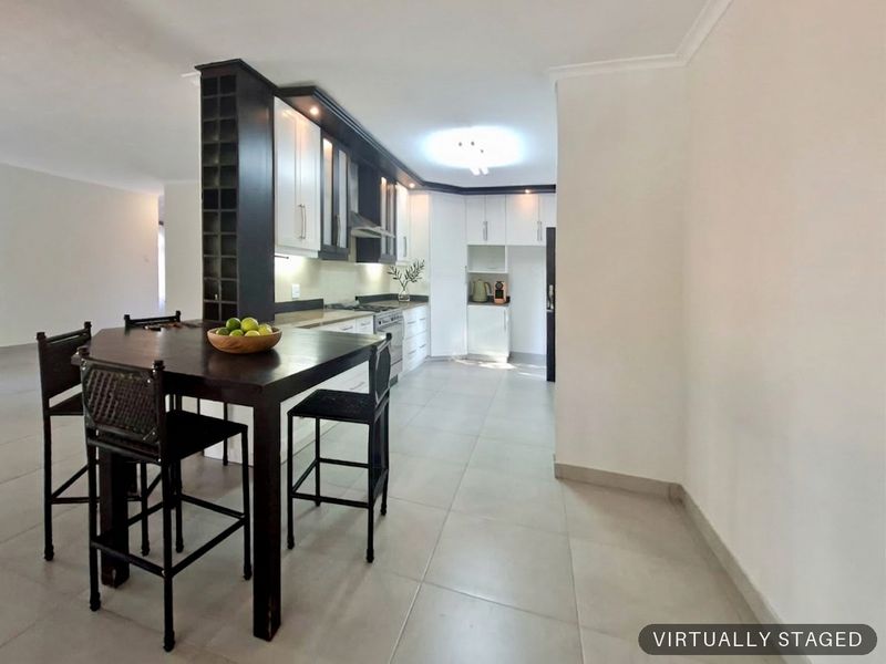 Modern kitchen featuring white cabinetry, dark accents, built-in appliances, and tiled flooring, seamlessly integrated with a dining area.