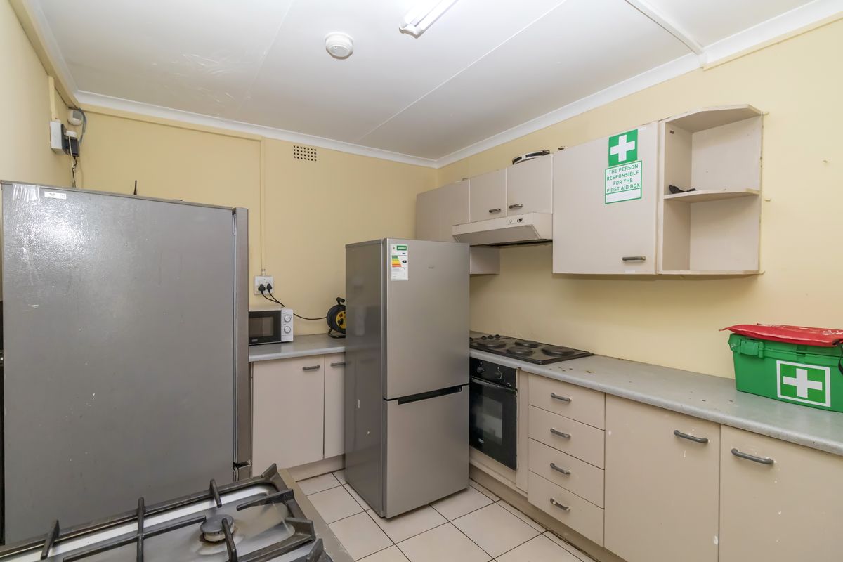 A functional kitchen featuring built-in cabinetry, laminate countertops, an electric hob, and an integrated oven, requiring cosmetic updates to modernize the space.