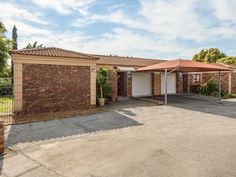 Front exterior view of a townhouse featuring a face brick facade, tiled roof, double garage, and a covered carport area.