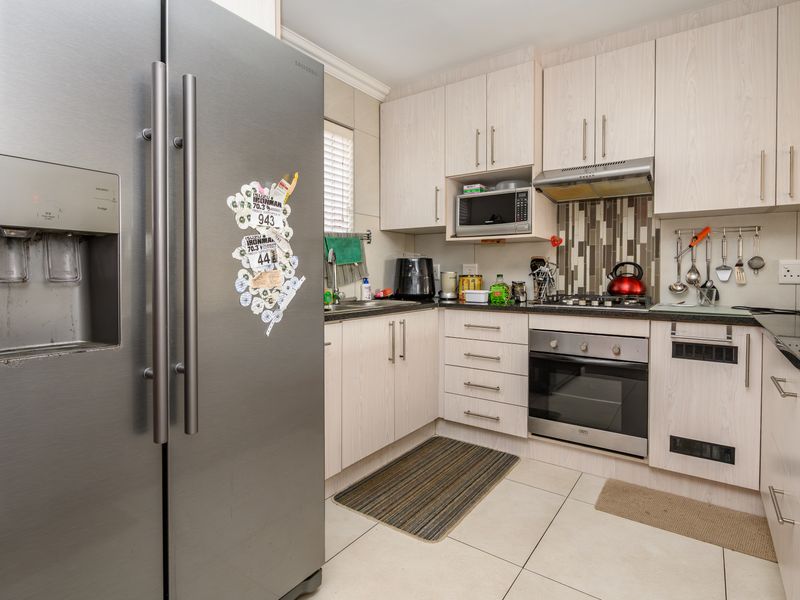 A functional kitchen featuring light wood-grain cabinetry, granite countertops, a gas hob, built-in oven, and tiled flooring with a modern backsplash.