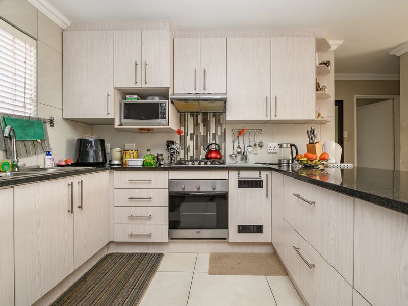 A functional kitchen featuring light wood-grain cabinetry, granite countertops, a built-in oven, gas hob, and a tiled backsplash.