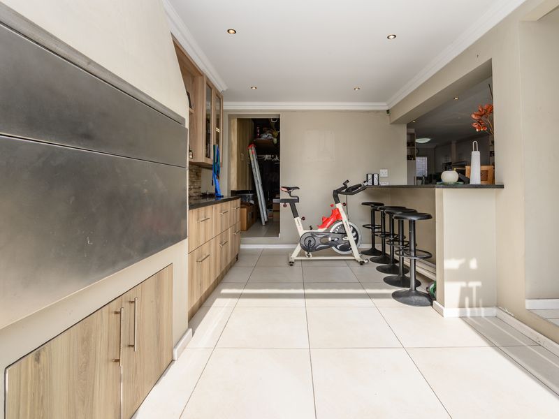 Covered patio area featuring a built-in braai, stone-topped cabinetry, and a breakfast bar, providing a functional space for outdoor entertaining.