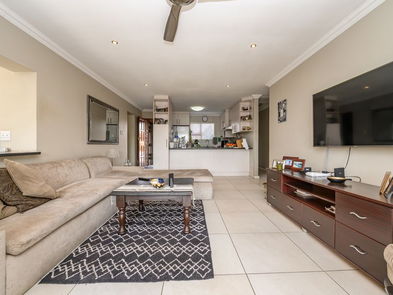 Spacious open-plan living area featuring tiled floors, recessed lighting, and a functional kitchen with a breakfast bar, creating a seamless flow for daily living.