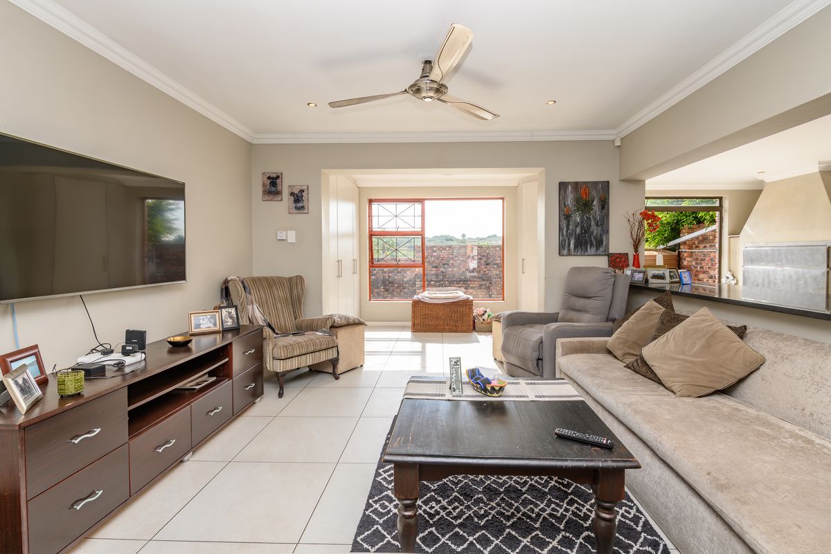 Spacious living room featuring tiled flooring, recessed lighting, a ceiling fan, and a breakfast bar connecting to the adjacent kitchen area.