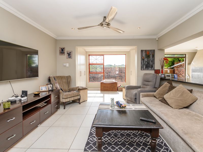 Spacious living room featuring tiled flooring, recessed lighting, a ceiling fan, and a breakfast bar connecting to the adjacent kitchen area.