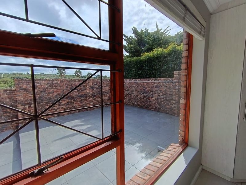 A view from an interior room looking out onto a private, tiled patio area enclosed by a brick boundary wall.
