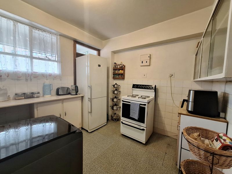 A functional kitchen featuring dated cabinetry, tiled splashbacks, and a freestanding stove, offering potential for modernization and cosmetic updates.