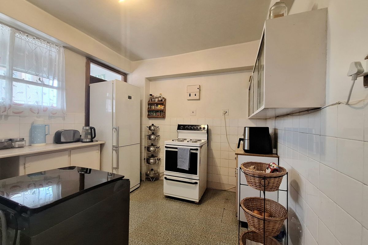 A functional kitchen featuring tiled splashbacks, built-in cabinetry, and a freestanding stove, offering potential for modernization and cosmetic updates.