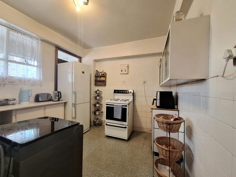 A functional kitchen featuring tiled splashbacks, built-in cabinetry, and a freestanding stove, offering potential for modernization and cosmetic updates.