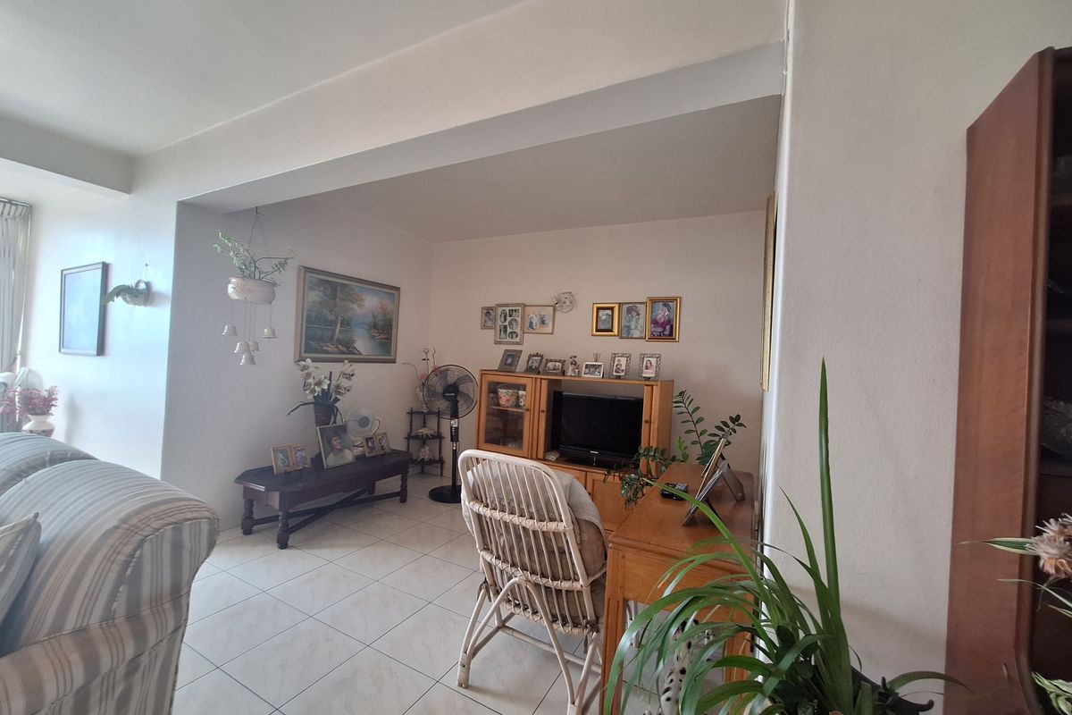 A living room area featuring tiled flooring and a structural ceiling beam, providing a functional and open living space.