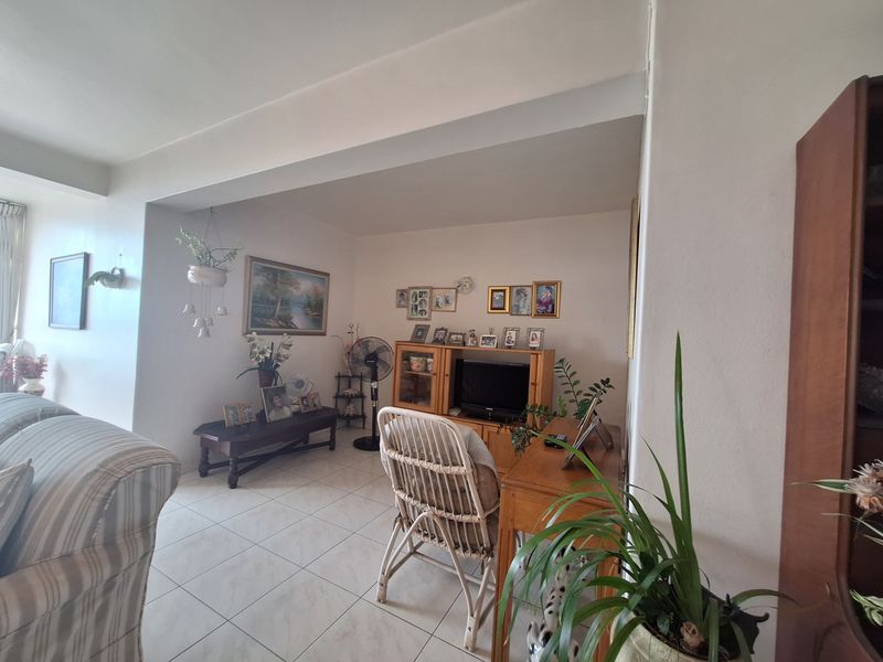 A living room area featuring tiled flooring and a structural ceiling beam, providing a functional and open living space.
