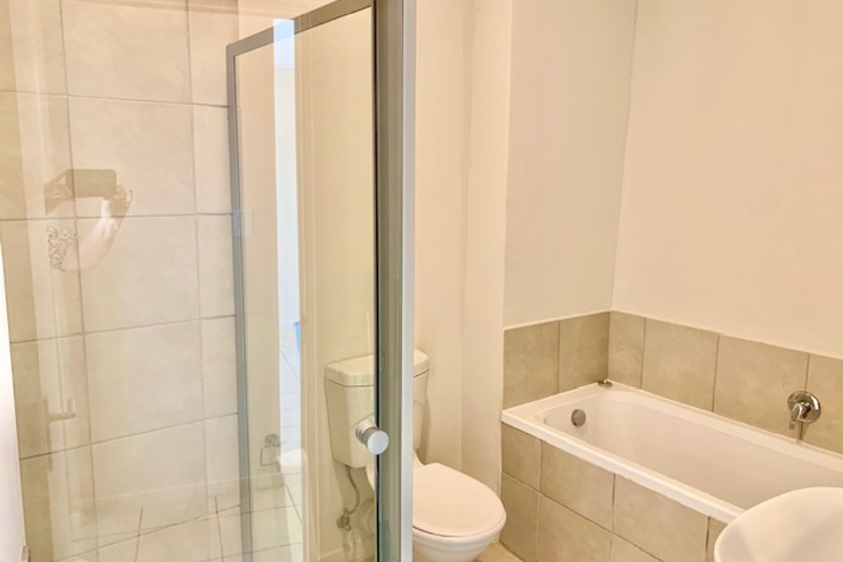 A functional bathroom featuring a separate shower enclosure, a bathtub with tiled surround, and a standard toilet.