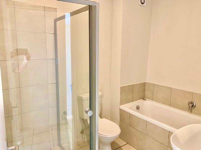 A functional bathroom featuring a separate shower enclosure, a bathtub with tiled surround, and a standard toilet.