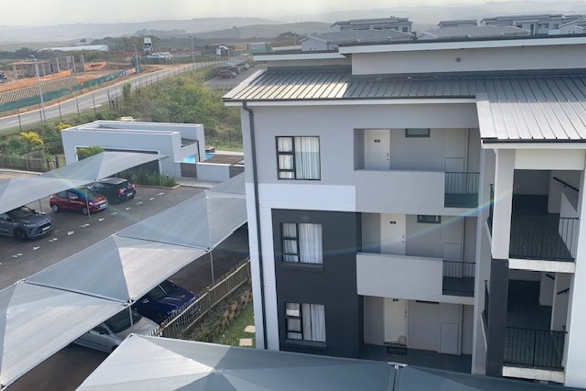 Aerial view of a modern apartment complex featuring covered parking bays and multi-level residential units with balconies.