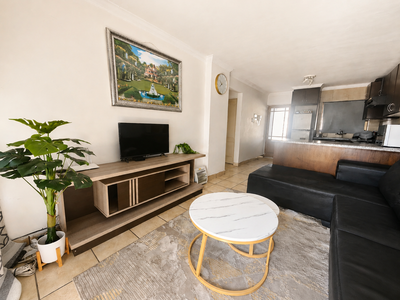 Open-plan living area featuring tiled floors and a functional kitchen with built-in cabinetry and granite countertops, creating a cohesive and practical living space.