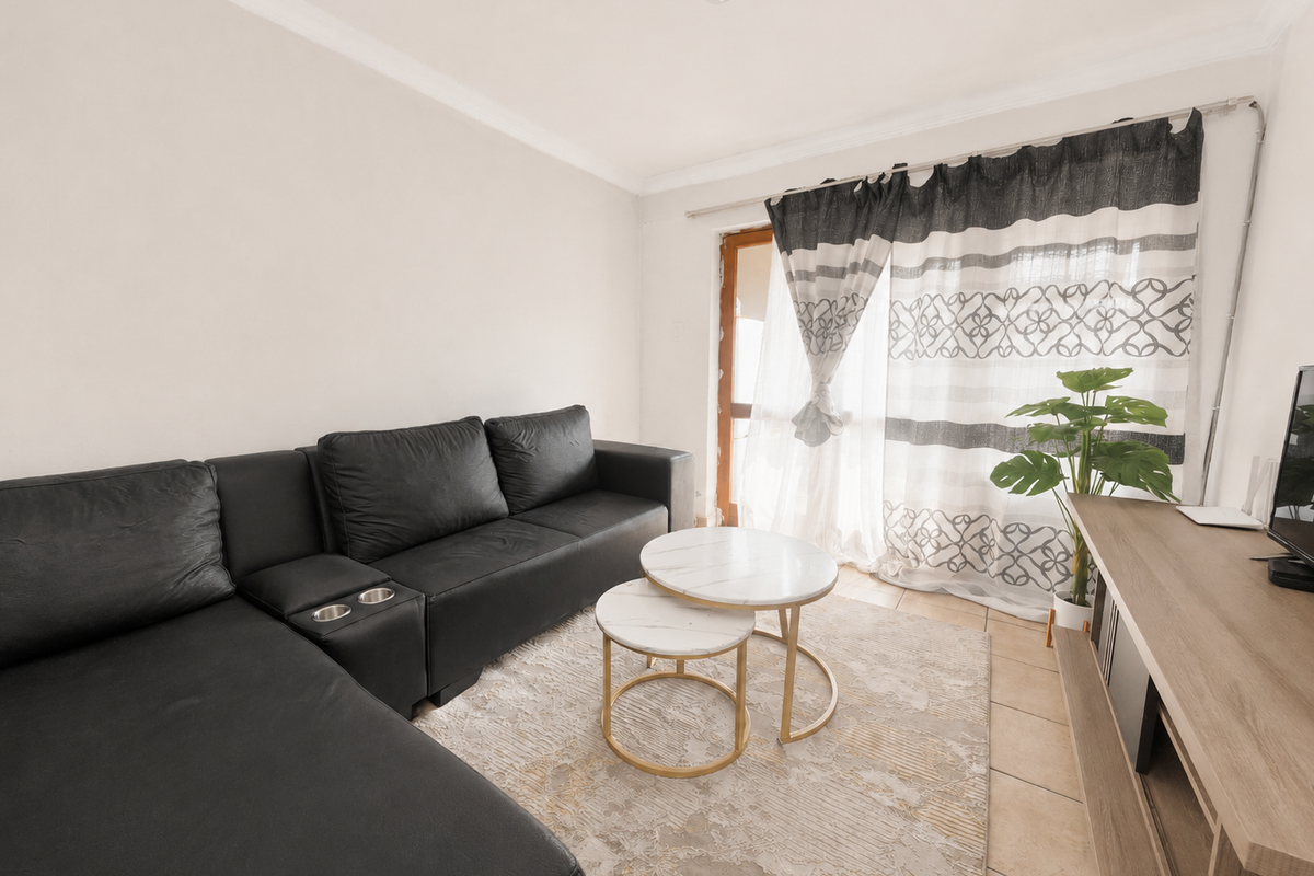 A living room featuring tiled flooring, a sliding glass door providing natural light, and decorative cove cornicing.