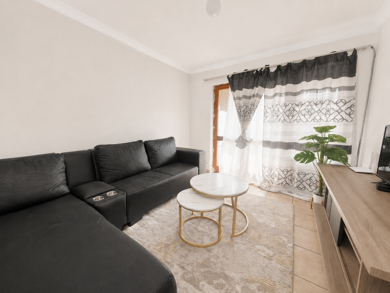 A living room featuring tiled flooring, a sliding glass door providing natural light, and decorative cove cornicing.