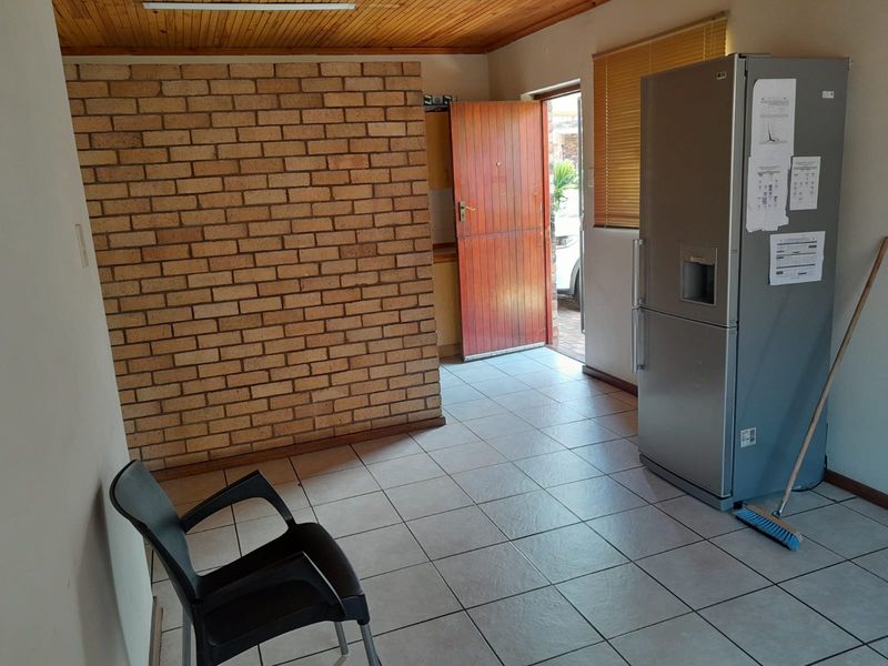 A functional kitchen area featuring exposed brickwork, timber ceiling paneling, and tiled flooring, providing a blank canvas for potential renovation and modernization.