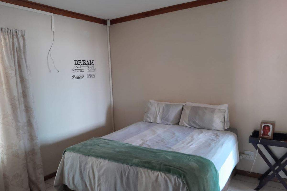 A simple bedroom featuring tiled flooring and timber ceiling trim, currently furnished with a double bed.