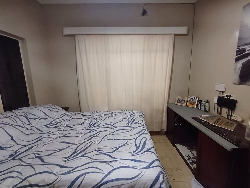 A bedroom featuring built-in cabinetry and a curtained window, requiring cosmetic updates to improve the overall aesthetic and condition of the space.