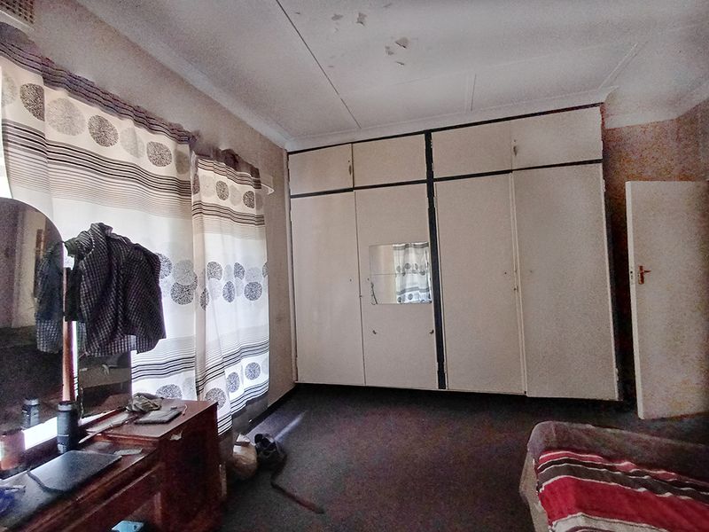 Bedroom featuring built-in cupboards and carpeted flooring, requiring cosmetic updates to the ceiling and finishes.
