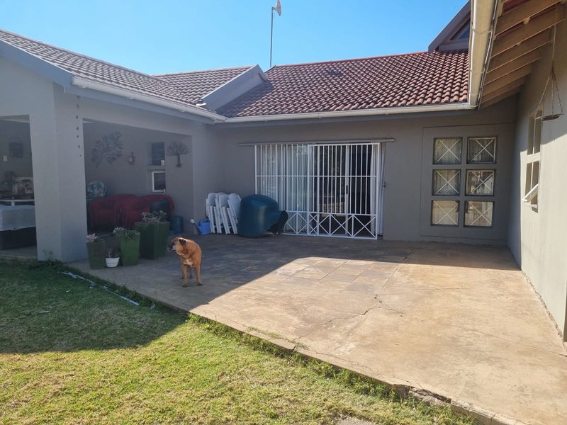 Rear view of the property featuring a covered patio area with concrete paving and access to the interior via a sliding glass door.