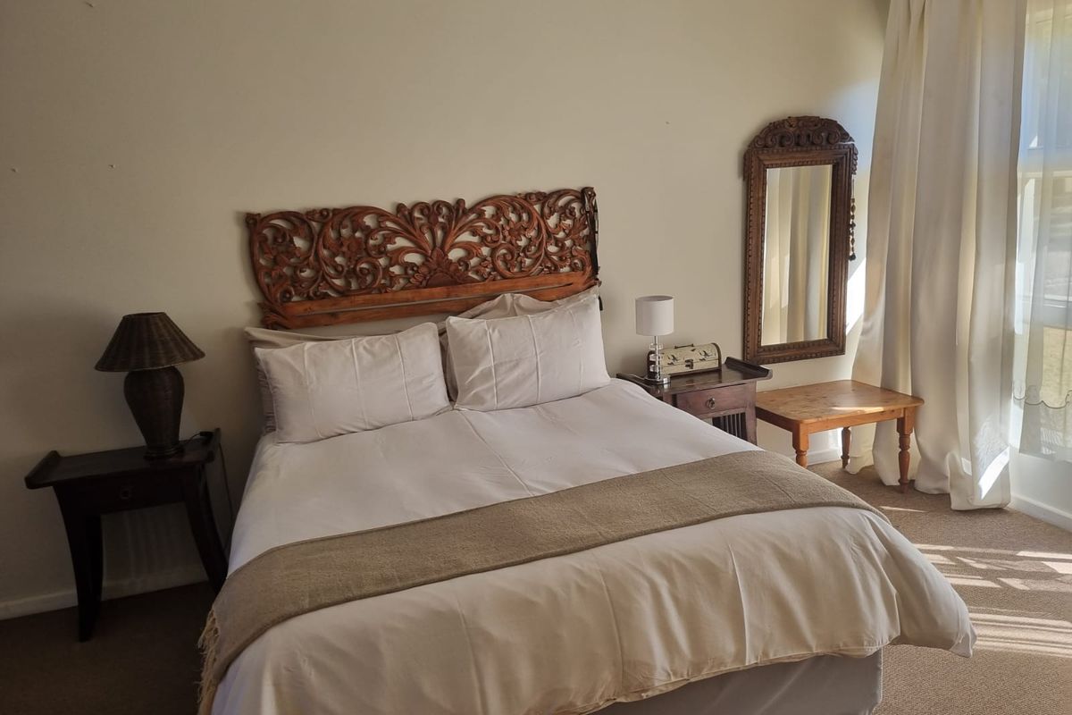A well-lit bedroom featuring neutral wall finishes, carpeted flooring, and window treatments, providing a comfortable and functional sleeping space.