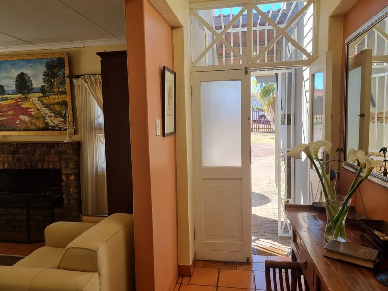 Entrance foyer featuring tiled flooring, a brick fireplace in the adjacent living area, and a classic frosted glass front door with transom window.