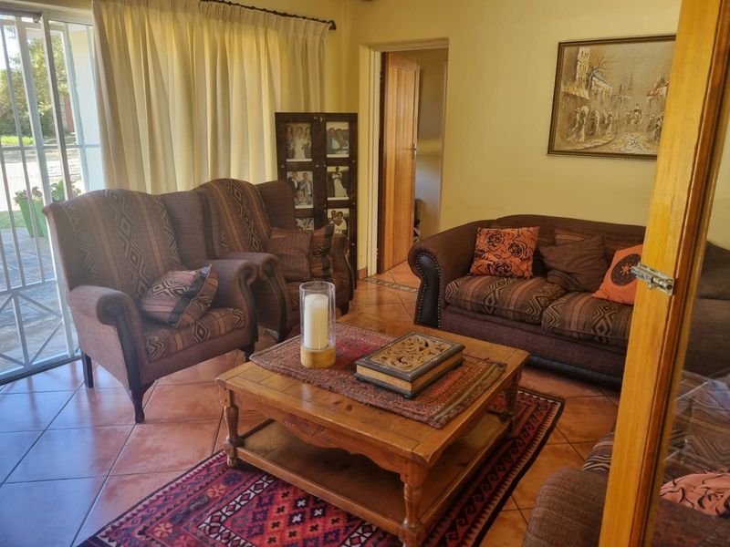 A comfortable living room featuring terracotta floor tiles and a sliding glass door providing access to the exterior.