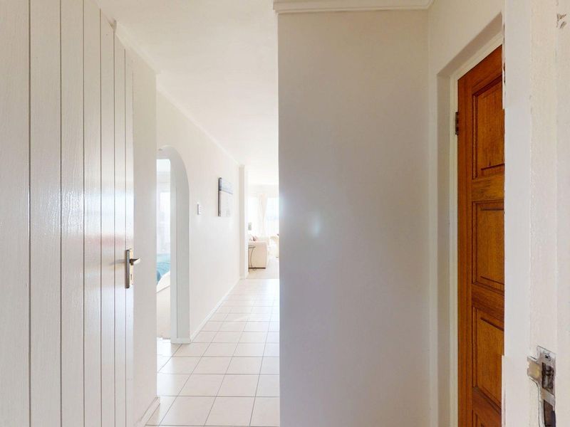 A bright, tiled hallway featuring an arched transition to the living area and multiple internal doors, providing a clean, neutral circulation space.