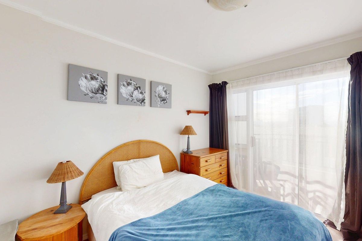 A well-lit bedroom featuring neutral walls, coving, and a large sliding glass door providing access to an outdoor area.